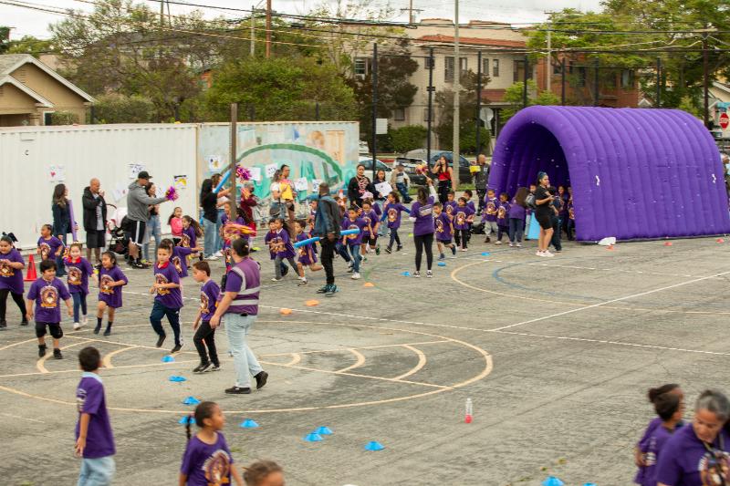 Students running with pool noodle cheer sticks