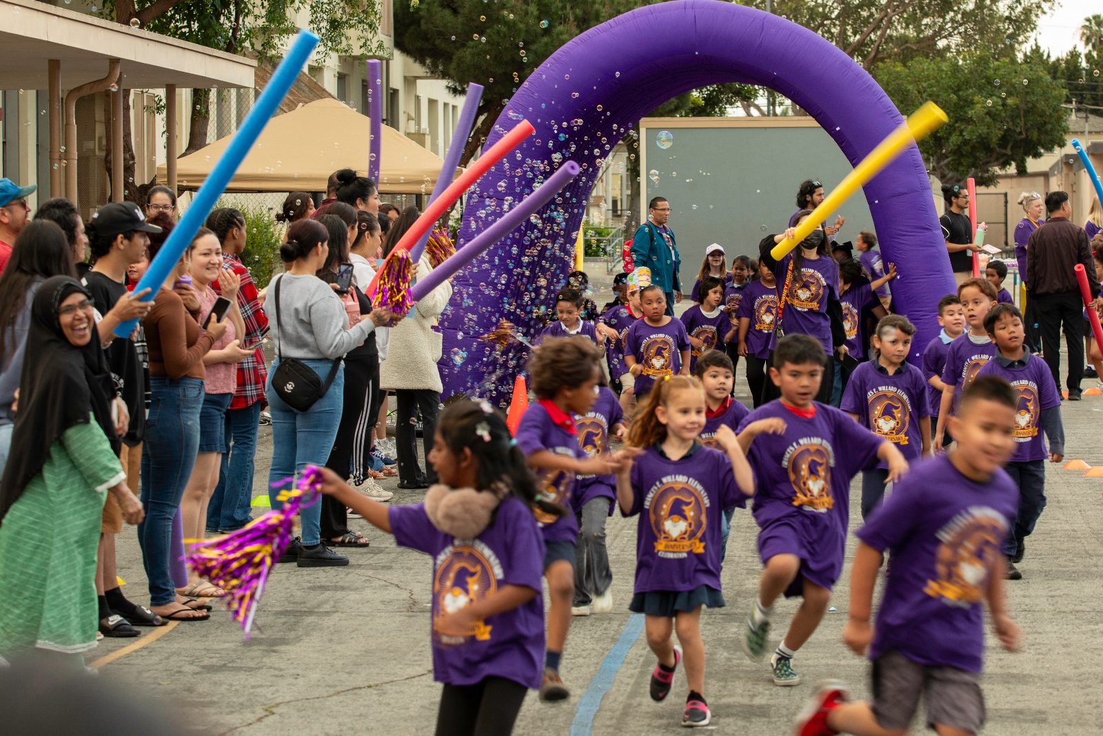 Willard students in purple Wizards shirts running through the bubble arch