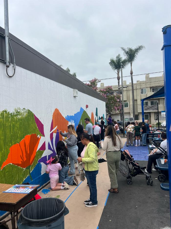 Student and volunteer painting green leaves